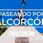 Estatua sobre pedestal en la zona centro de Alcorcón frente a un cielo azul y árboles, con texto superpuesto que promociona Paseando por Alcorcón y Zona Centro, Rebelión vecinal en Alcorcón contra la meca okupa del centro