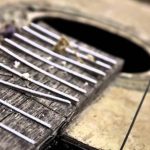 Primer plano de guitarra acústica con cuerdas desgastadas, evocando Barrio okupa de Alicante con renta media de 16.868 € y amenazas en entorno urbano