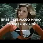 Mujer con gesto desafiante y manos en caderas frente a un fondo de árboles, vestida con un conjunto retro de colores vivos y texto superpuesto que lee "ERES RETE FLOJO MANO YA NO TE QUIERO", María enfrenta a su inquiokupa en la puerta de enfrente.