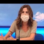 Una mujer con mascarilla, sentada en una mesa y gesticulando, mientras habla sobre temas relacionados con la seguridad y la ley, en el contexto de un anuncio donde se informa sobre el desmantelamiento de una red de narcotraficantes que ocupaban viviendas en la localidad de Vilamarxant, Valencia. Desmantelan red de narco okupas en Vilamarxant Valencia.