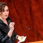 Mujer gesticulando en un hemiciclo con chaqueta de cuero negra, sosteniendo notas y hablando frente a un micrófono sobre un fondo de madera, Albiol solicita a defensores de acoger que reciban a okupas en Badalona