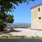 Plaza soleada con edificio de piedra, árboles y vistas a la sierra, Okupas, prostitución y quejas en un pueblo de Mallorca